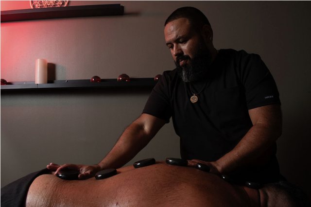Carlos Blanco placing hot stones along the back
